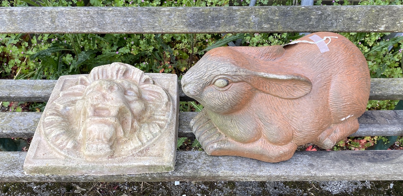 A terracotta rabbit garden ornament length 50cm, and a reconstituted stone lion mask wall appliqué